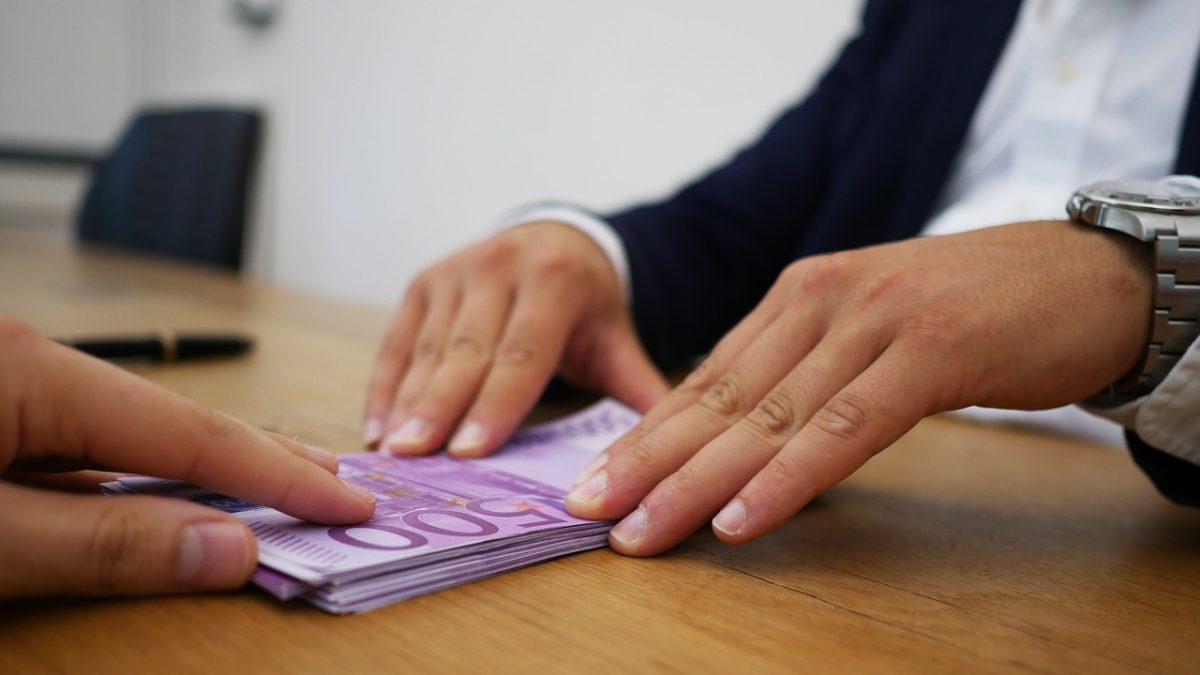 en man skjuter över pengar till den andre för att illustrera en företagsöverlåtelse