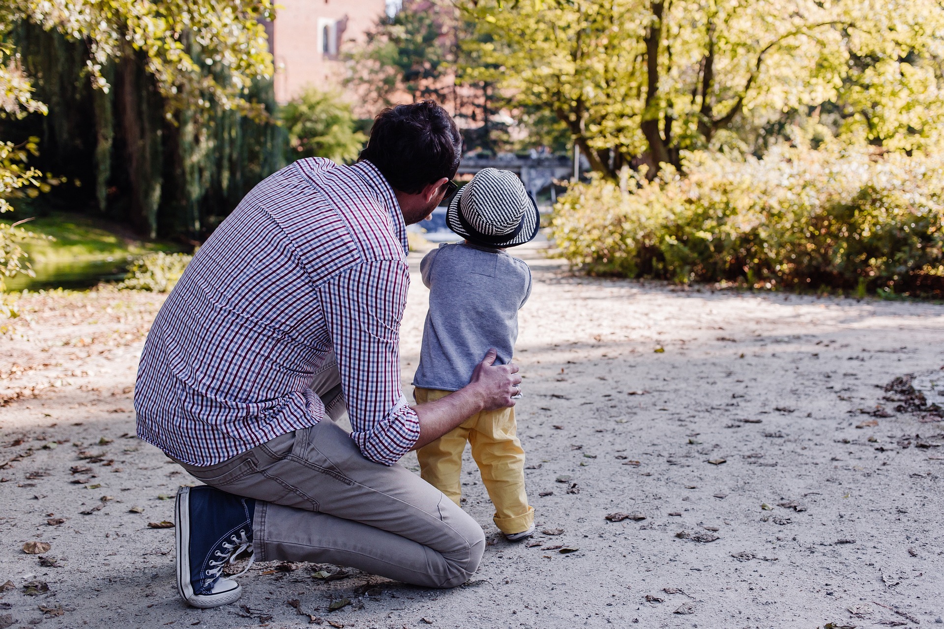 generationsskifte en pappa står på huk med sin son och pekar mot ett träd längre ner på vägen det står på